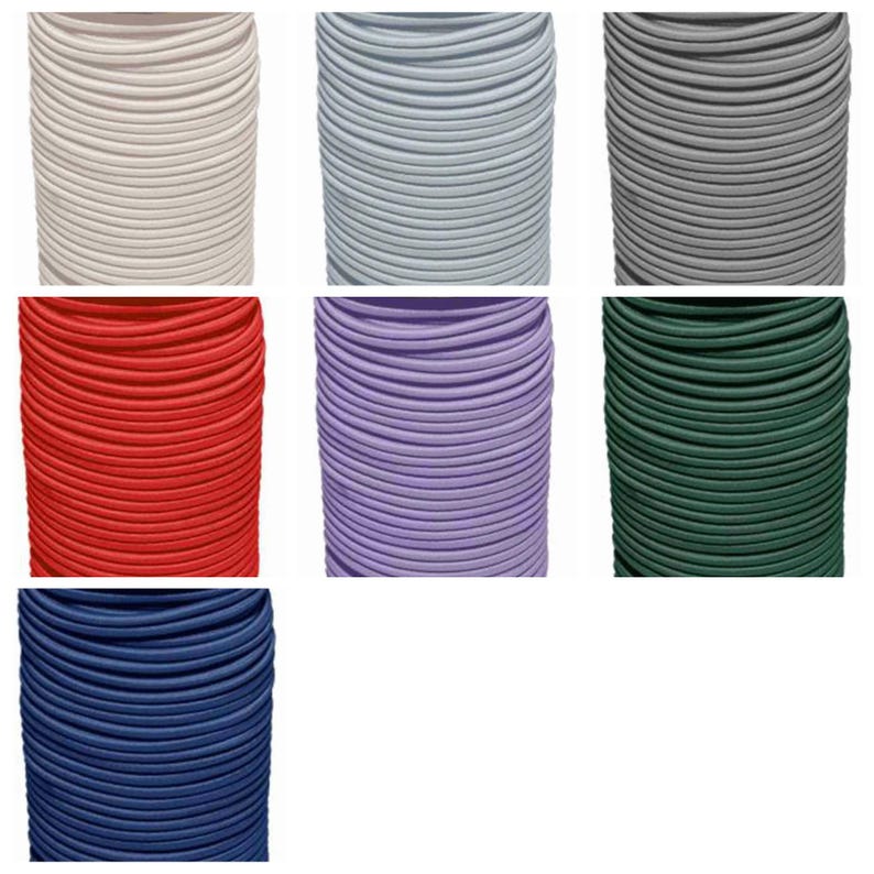 May include: A collection of seven spools of elastic cord in various solid colors including white, light blue, gray, red, purple, dark green, and navy blue. Each spool features a tightly wound, smooth, cylindrical cord with a consistent texture.