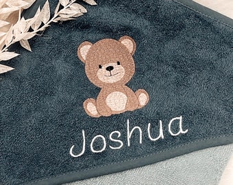 May include: A dark blue hooded towel with a brown embroidered bear and the name "Joshua" in white embroidery.
