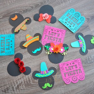 以下が含まれることがあります： 黒と白のミッキーマウスの頭の切り抜き9個セット。カラフルな紙の飾り付き。飾りには、ソンブレロ、花、そして「Let's Fiesta」と「Feliz Fiesta」と書かれた紙の旗が含まれています。