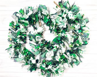 May include: A green and white fabric garland with shamrock patterns. The garland is made of strips of fabric that have been frayed and tied together. It is a festive decoration for St. Patrick's Day.