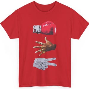 Peut inclure: T-shirt rouge avec un motif graphique repr&eacute;sentant un gant de boxe rouge, une main orn&eacute;e de bagues dor&eacute;es et une main faisant le signe de la paix. Le design est de style collage.