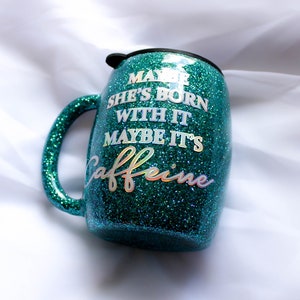 Peut inclure: Un gobelet en plastique scintillant vert turquoise avec un couvercle et une poign&eacute;e noirs. Le gobelet est d&eacute;cor&eacute; d'un autocollant en vinyle blanc avec le texte "Maybe she's born with it, maybe it's caffeine."