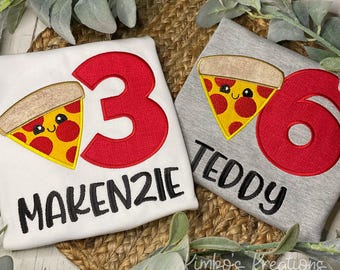 May include: Two white and grey t-shirts with red and yellow embroidered pizza slices and numbers. The white shirt says "Makenzie 3" and the grey shirt says "Teddy 6".