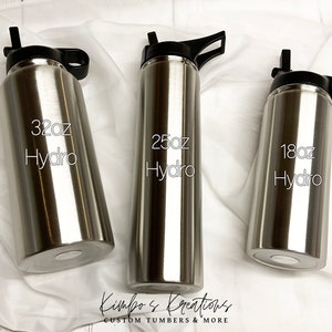 Peut inclure: Trois bouteilles d'eau en acier inoxydable avec des couvercles et des poign&eacute;es noirs. Les bouteilles sont &eacute;tiquet&eacute;es avec le texte "32oz Hydro", "25oz Hydro" et "18oz Hydro".