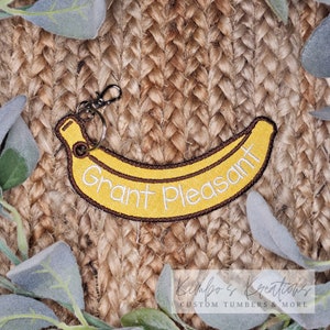 May include: A yellow banana-shaped keychain with the text "Grant Pleasant" embroidered in brown thread.