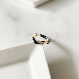 May include: A tortoiseshell-patterned ring with a square shape. The ring is made of plastic and has a glossy finish.