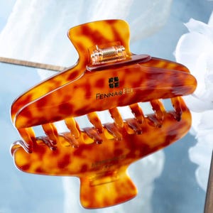 May include: A tortoise shell patterned hair claw clip with a glossy finish. The clip features a gold-toned metal spring mechanism and the text FENNA&FEI printed in gold lettering on the front, accompanied by a small four-leaf clover logo.