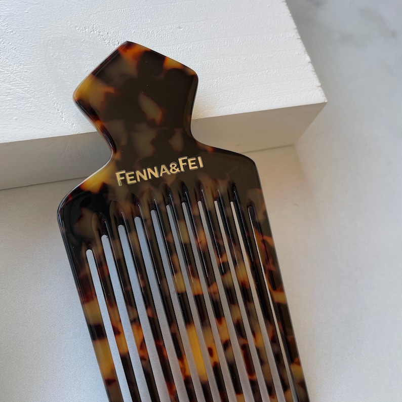 K&ouml;nnte beinhalten: Ein Kamm aus Schildpatt mit einer einzigartigen, spitzen Oberseite. Der Kamm tr&auml;gt eine goldene Inschrift mit der Aufschrift "Fenna & Fei".