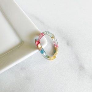 May include: A colorful, translucent ring with a swirl pattern in shades of pink, blue, yellow, and green.