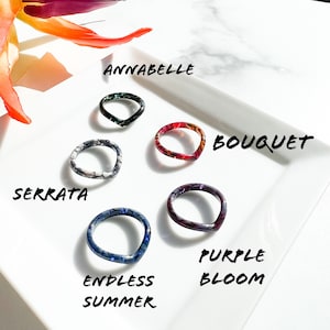 May include: Five colorful resin rings with different patterns and names: Annabelle, Bouquet, Serrata, Endless Summer, and Purple Bloom.