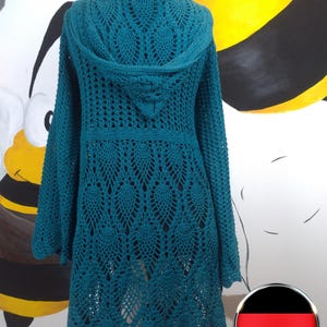 Op de afbeelding: Turquoise gebreide cardigan met een capuchon en lange mouwen. De cardigan heeft een delicaat opengewerkt patroon.