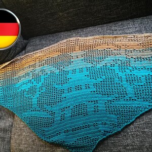 May include: A crocheted shawl with a gradient of colors, starting with a light brown and transitioning to a teal blue. The shawl is made with a delicate open stitch pattern.