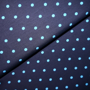 Könnte beinhalten: Nahaufnahme eines dunkelblauen Stoffes mit einem sich wiederholenden Muster aus hellblauen Punkten.