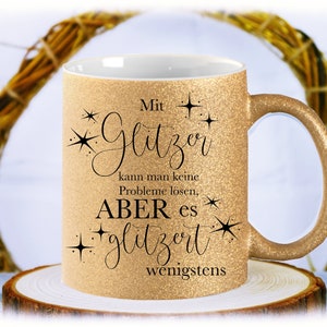 Könnte beinhalten: Goldene Glitzer-Tasse mit schwarzer Aufschrift: "Mit Glitzer kann man keine Probleme lösen, ABER es glitzert wenigstens".