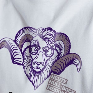 Peut inclure: T-shirt blanc avec un graphique violet et gris d'une tête de bélier avec le texte "HEUTE NULL BOCK MODUS" en dessous. Le texte est dans une boîte grise.