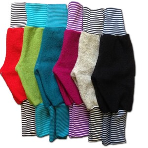 May include: A set of seven pairs of colorful fleece leggings with striped cuffs. The leggings are in red, green, teal, pink, gray, and black.