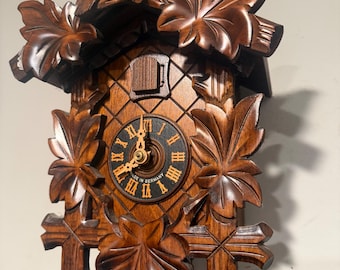 Reloj de cuco con pesas de madera y manecillas de madera.