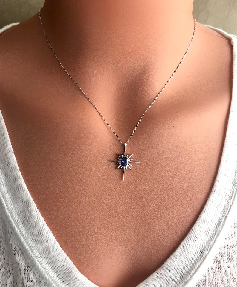 K&ouml;nnte beinhalten: Eine silberne Halskette mit einem blauen Edelstein-Sternenanh&auml;nger.