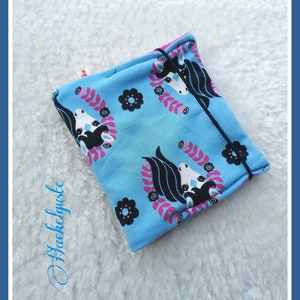 Könnte beinhalten: Eine blaue und pinke Stofftasche mit einem schwarzen und weißen Einhorn-Druck. Die Tasche ist gefaltet und hat einen schwarzen Kordelzug.