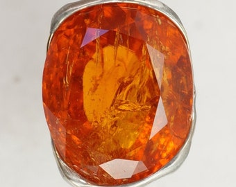 May include: A silver pendant with a large, faceted, orange gemstone. The gemstone is set in a silver bezel.