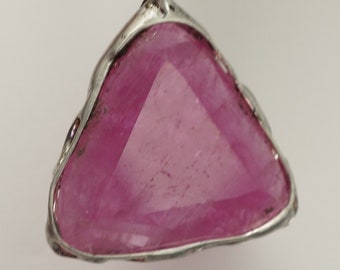 May include: A triangular pink gemstone pendant with a silver setting. The pendant is hanging from a silver chain.