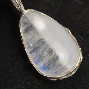 May include: A silver pendant with a teardrop-shaped moonstone. The stone is clear with a blue sheen.
