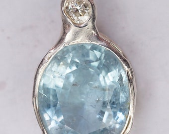 Può includere: Un ciondolo d'argento con una pietra preziosa acquamarina blu chiaro e un piccolo accento di diamante.