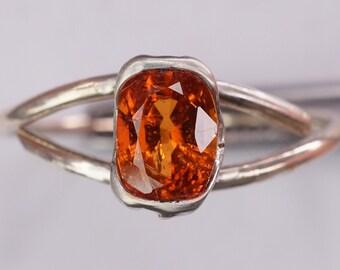 May include: A silver ring with an orange gemstone set in a bezel setting.