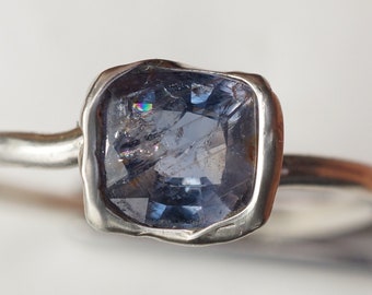 Puede incluir: Un anillo de plata con una piedra preciosa azul engastada en un engaste texturizado.
