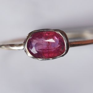 May include: A silver ring with a pink oval gemstone set in a textured bezel.