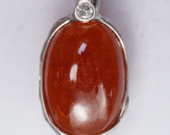 May include: A silver pendant with a large, oval-shaped, orange gemstone and a small, round, clear diamond.