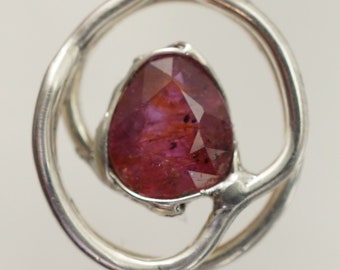 May include: A silver pendant featuring a pink gemstone set within a circular design.
