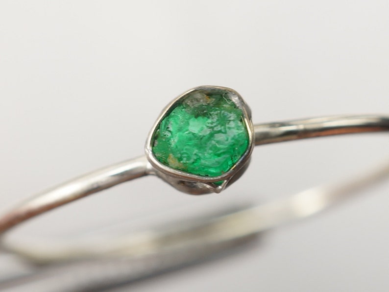 Peut inclure: Une bague en argent avec une &eacute;meraude verte sertie dans un sertissage &agrave;  bezel.