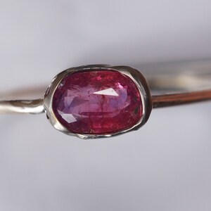 May include: A silver ring with a pink oval gemstone set in a textured bezel.