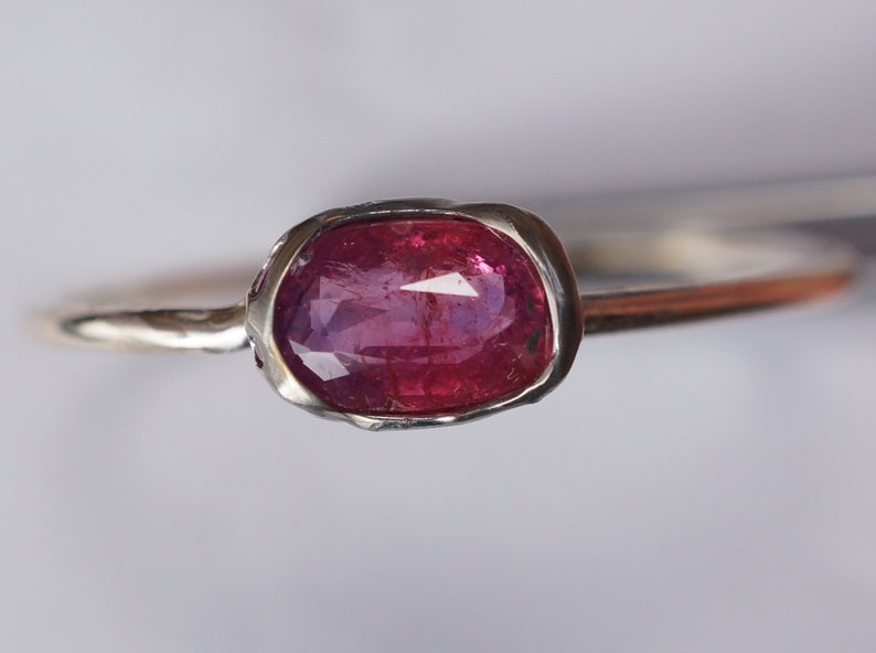 May include: A silver ring with a pink oval gemstone set in a textured bezel.