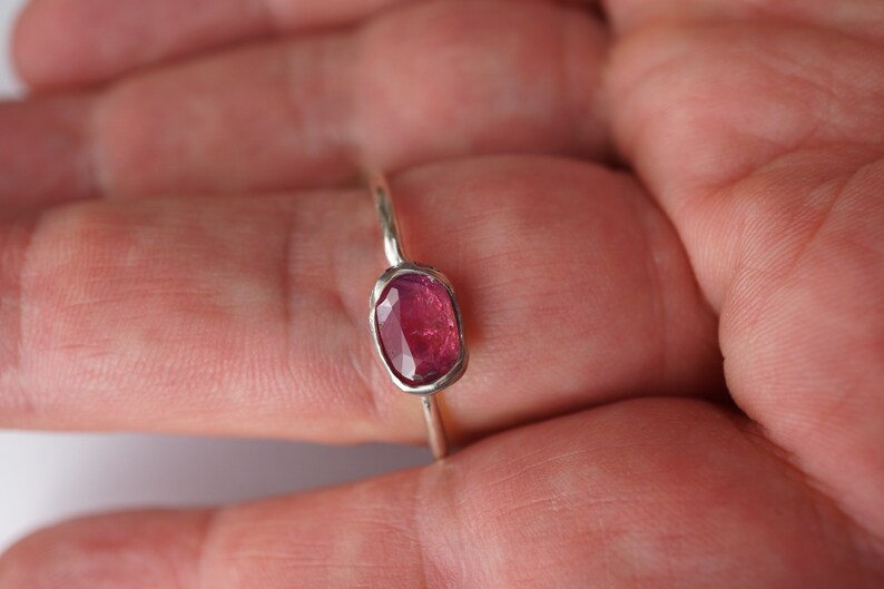 May include: A silver ring with a pink oval gemstone.