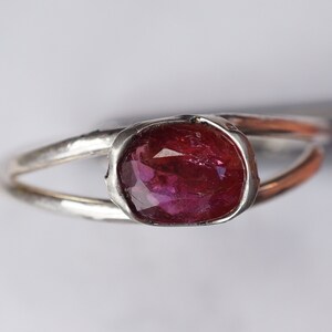 Puede incluir: Un anillo de plata con una piedra ovalada rosa engastada en un engaste de bisel.