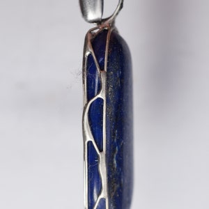 May include: A silver pendant with a dark blue lapis lazuli stone set in a delicate, openwork design.