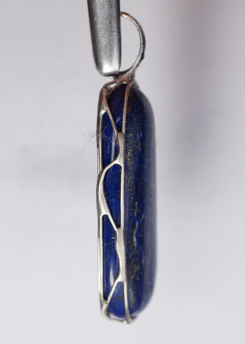 May include: A silver pendant with a dark blue lapis lazuli stone set in a delicate, openwork design.