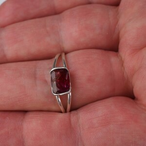 Pu&ograve; includere: Un anello d'argento con una pietra rettangolare di colore rosso scuro.