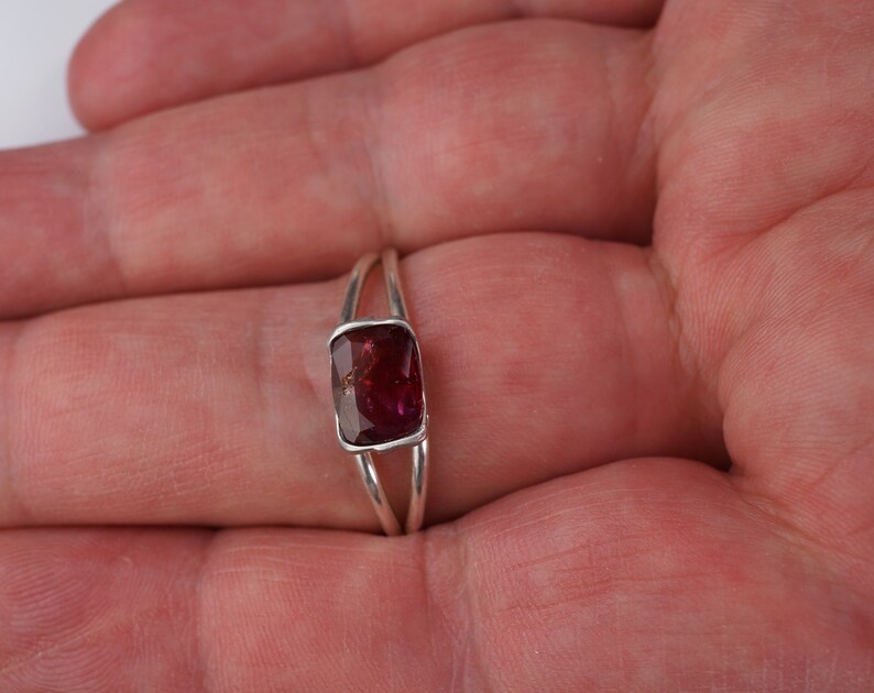 Pu&ograve; includere: Un anello d'argento con una pietra rettangolare di colore rosso scuro.