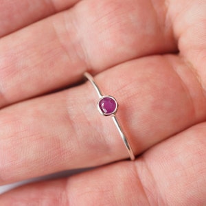 K&ouml;nnte beinhalten: Ein schlichter Silberring mit einem kleinen, runden, rosafarbenen Edelstein.