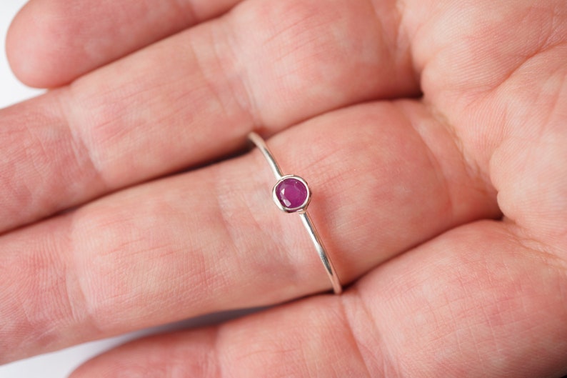 K&ouml;nnte beinhalten: Ein schlichter Silberring mit einem kleinen, runden, rosafarbenen Edelstein.