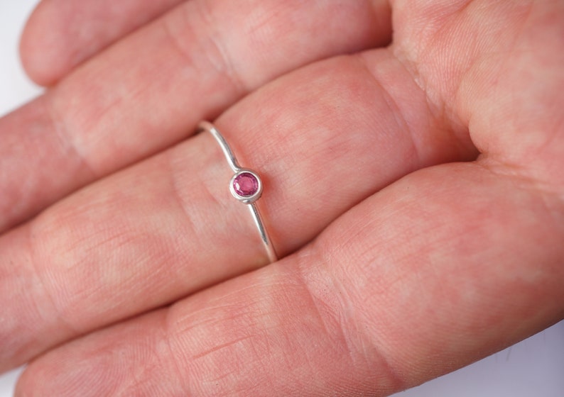 K&ouml;nnte beinhalten: Ein zarter Silberring mit einem kleinen, runden, rosafarbenen Edelstein.