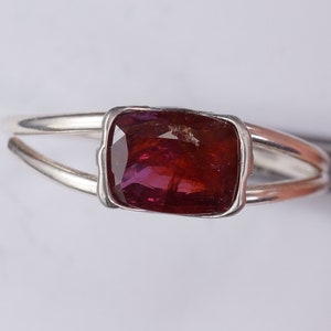 Pu&ograve; includere: Un anello d'argento con una pietra preziosa rettangolare di colore rosso scuro incastonata in una montatura a castone.