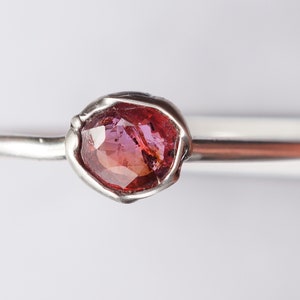 Op de afbeelding: Een zilveren ring met een roze edelsteen in een bezel setting.