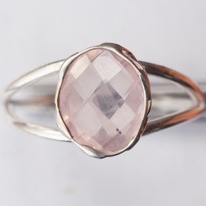 Puede incluir: Un anillo de plata con una piedra ovalada de color rosa claro. La piedra est&aacute; facetada y tiene un borde delicado ligeramente ondulado.