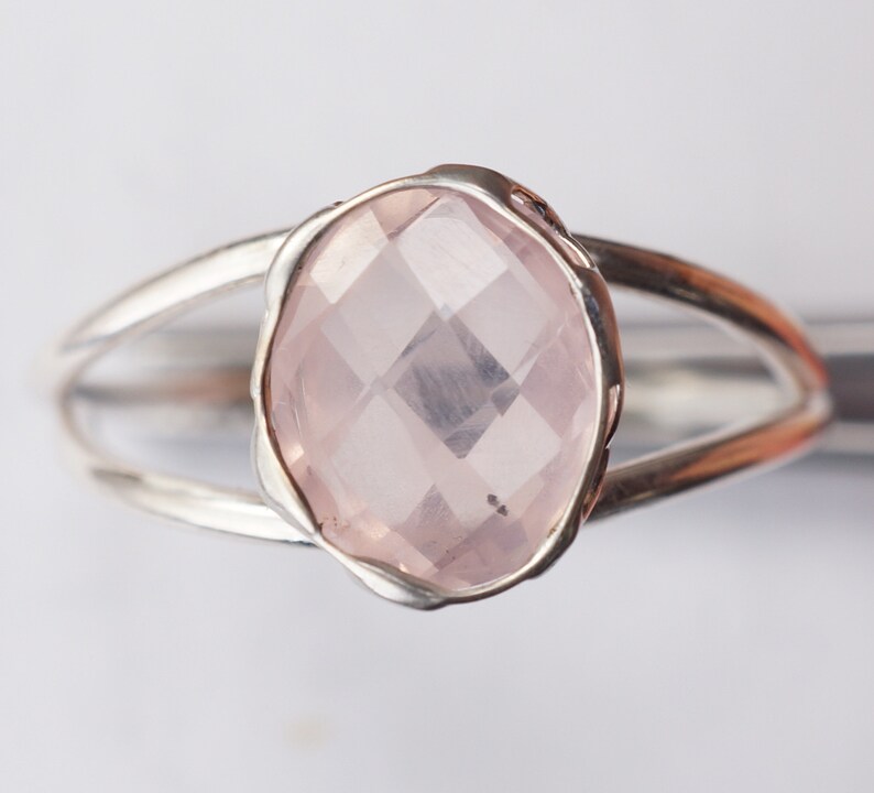 Puede incluir: Un anillo de plata con una piedra ovalada de color rosa claro. La piedra est&aacute; facetada y tiene un borde delicado ligeramente ondulado.