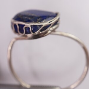 Puede incluir: Un anillo de plata con una gran piedra de lapisl&aacute;zuli azul engastada en una delicada jaula de alambre.
