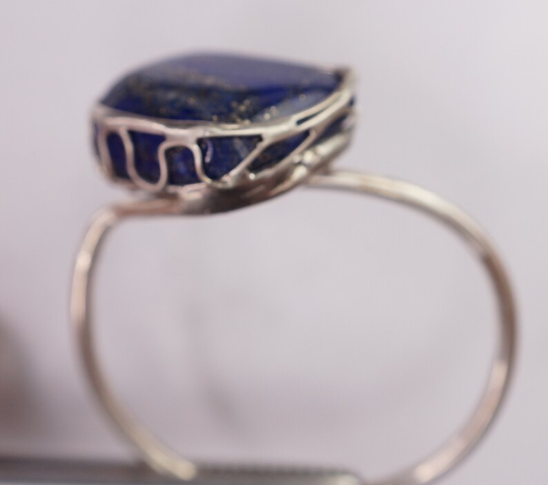 Puede incluir: Un anillo de plata con una gran piedra de lapisl&aacute;zuli azul engastada en una delicada jaula de alambre.